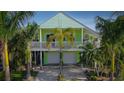 A two-story home with a two-car garage, a balcony and a beautifully landscaped yard with mature palms at 112 13Th Ave, Indian Rocks Beach, FL 33785