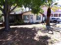 Cozy single-story home with a screened porch and shade trees on a sunny day at 1436 Ohio Ave, Palm Harbor, FL 34683
