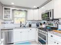 Well-lit kitchen featuring white cabinets, stainless steel appliances, and a charming window above the sink at 5433 Palmetto Rd, New Port Richey, FL 34652