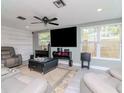 Modern living room featuring a large flat-screen TV, ceiling fan, and comfortable seating arrangement at 5433 Palmetto Rd, New Port Richey, FL 34652