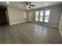 Spacious living room featuring durable wood-look flooring, a ceiling fan, and a well-lit ambiance at 7323 Andre Dr, Zephyrhills, FL 33541