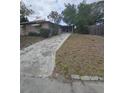 Showing the backyard of the home and the home's exterior, featuring a concrete walkway at 7735 Gaston Dr, Port Richey, FL 34668