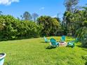 Spacious backyard with lush green grass and outdoor seating arranged around a charming firepit at 13420 Rustic Pines S Blvd, Seminole, FL 33776