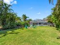Lush backyard featuring a screened-in pool, a firepit, and tropical landscaping at 13420 Rustic Pines S Blvd, Seminole, FL 33776