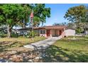 Inviting single-Gathering home with lush green lawn, mature trees, and an American flag at 202 New Hope Rd, Brandon, FL 33510