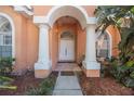 Elegant home entrance featuring stately white columns and lush tropical landscaping at 2302 Azalea Dr, Palm Harbor, FL 34683