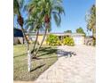 Charming single-story home featuring a well-manicured lawn, brick driveway, and tropical palm trees at 4126 Harrisburg Ne St, St Petersburg, FL 33703