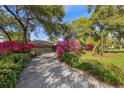 Long brick paver driveway leading to a well-maintained home with lush, colorful landscaping at 8823 Crescent Forest Blvd, New Port Richey, FL 34654