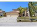 Inviting two-story home featuring a large driveway, mature trees, and lush landscaping at 12929 Prestwick Dr, Riverview, FL 33579