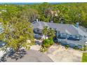 An aerial view shows the townhome surrounded by mature trees and landscaping with a glimpse of the bay in the distance at 1955 Georgia N Cir, Clearwater, FL 33760