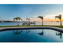 Tranquil pool reflecting the sunset and palm trees on the waterfront property at 200 Driftwood W Dr, Palm Harbor, FL 34683