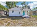 Charming white home showcasing a cheerful turquoise door and well-maintained front yard at 2111 E Ellicott St, Tampa, FL 33610