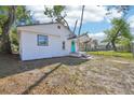 Delightful white home with a vibrant blue door and a cozy front porch, surrounded by lush greenery at 2111 E Ellicott St, Tampa, FL 33610