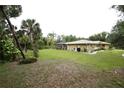 Expansive backyard featuring a well-maintained lawn, mature trees, and a screened lanai for outdoor enjoyment at 229 Tazewell Dr, Port Charlotte, FL 33954