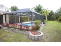 A beautiful screened pool with a surrounding stone retaining wall and manicured plants at 229 Tazewell Dr, Port Charlotte, FL 33954