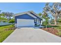 Inviting blue home featuring a well-kept lawn, fresh landscaping, and an attached two-car garage at 2807 W Granfield Ave, Plant City, FL 33563