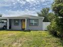 Cozy home featuring a sunny yellow front door, convenient carport, and well-maintained lawn at 3106 W Dewey, Tampa, FL 33607