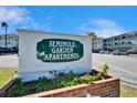 Seminole Garden Apartment complex sign with colorful flower beds and blue skies above at 8454 111Th St # 201, Seminole, FL 33772