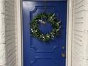 Charming front door painted in a dark blue with a decorative green wreath at 100 Bluff View Dr # 117C, Belleair Bluffs, FL 33770