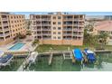 Aerial view of condo buildings and docks with boat lifts and boats, plus a community pool at 11525 Gulf Blvd # 401, Treasure Island, FL 33706