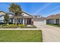 Charming single-Gathering home featuring a well-manicured lawn, landscaping, and attached garage at 14885 Caravan Ave, Odessa, FL 33556