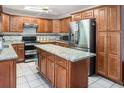 A spacious kitchen with granite countertops, wood cabinetry, stainless steel appliances, and a center island at 16405 Ashwood Dr, Tampa, FL 33624