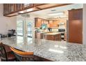 Kitchen view with granite countertops and wood cabinetry, with view into the backyard via glass patio doors at 16405 Ashwood Dr, Tampa, FL 33624