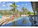 Backyard pool featuring rock features, and tropical palm trees create a private oasis at 19530 Barrie Acres Trl, Odessa, FL 33556
