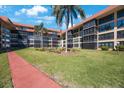 Well-maintained courtyard with lush green lawn, palm trees and building with screened balconies at 19701 Gulf Blvd # 231, Indian Shores, FL 33785