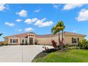 Charming tan home with a terracotta-tiled roof, beautiful landscaping, and a lengthy driveway approach at 3487 Recurve Cir, Sarasota, FL 34240