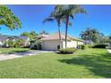 View of the home's side featuring mature palm trees, well-kept lawn, and an attached two-car garage at 4904 Breyer Wood Ct, Valrico, FL 33596