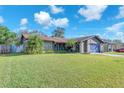 Charming single-story house with a lush green lawn, blue garage, and palm trees at 808 Centerwood Ct, Brandon, FL 33511