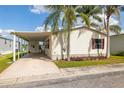 Charming single-story home with covered carport, lush lawn, and mature palm trees under a sunny blue sky at 8632 Fantasia Park Way, Riverview, FL 33578