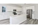 Modern kitchen with white cabinets, stainless steel appliances, a center island and gray wood floors at 9764 Crescent Moon Dr, Riverview, FL 33578