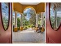 Elegant front porch with stone flooring and rocking chair, framed by decorative columns at 13514 Thoroughbred Dr, Dade City, FL 33525