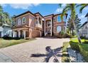 Stunning multi-story Mediterranean home with manicured lawn, brick driveway, and barrel tile roof at 1408 Alhambra Dr, Apollo Beach, FL 33572