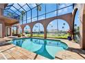 Beautiful in-ground swimming pool with screened enclosure, archways, and sun lounge area at 1408 Alhambra Dr, Apollo Beach, FL 33572