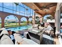 Relaxing outdoor pool area with seating, ceiling fans, and a fire pit table at 1408 Alhambra Dr, Apollo Beach, FL 33572