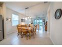 An open floorplan dining room with a wooden table and chairs beneath a modern pendant light fixture at 19212 Iron Topsail Isle, Land O Lakes, FL 34638