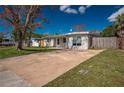 Exterior view showing the home's driveway and well-maintained lawn with mature trees at 5411 96Th N Ter, Pinellas Park, FL 33782