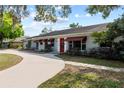 Charming single-story home with red door, awning-covered windows, and a curved driveway at 705 S West Shore Blvd, Tampa, FL 33609