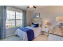 Cozy bedroom with a comfortable bed, bright window, and stylish blue accents at 7174 Beaverhead Ln, Land O Lakes, FL 34638