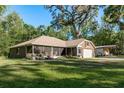 Spacious home with a screened porch, an attached garage, detached garage and expansive green lawn with mature trees at 7182 Griffin Rd, Brooksville, FL 34601
