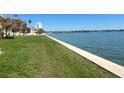 Waterfront grassy area of condo with a beautiful bay view on a sunny day with trees and a condo in the distance at 7500 Sunshine Skyway S Ln # T6, St Petersburg, FL 33711
