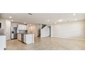 Spacious open-concept living room with tile flooring connecting the kitchen, dining, and staircase at 9832 Crescent Moon Dr, Riverview, FL 33578