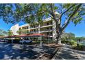 Exterior view of condo building with covered parking, mature trees, and sidewalk at 11485 Oakhurst Rd # A202, Largo, FL 33774