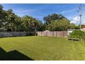 Spacious backyard with a well-maintained lawn, wooden fence, mature trees, and partial shade at 1836 Bayou Grande Ne Blvd, St Petersburg, FL 33703