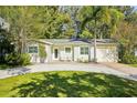 Charming single-story home featuring a well-manicured lawn, palm tree, and cozy front seating area at 1908 Sutherland W Dr, Palm Harbor, FL 34683