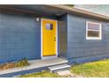 Close-up of a vibrant yellow front door with the house number 201, set against blue siding at 201 83Rd N Ave, St Petersburg, FL 33702