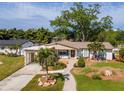 Charming single-story home features a brick pathway, lush landscaping, and a carport, nestled among mature trees at 201 S Treasure E Dr, Tampa, FL 33609